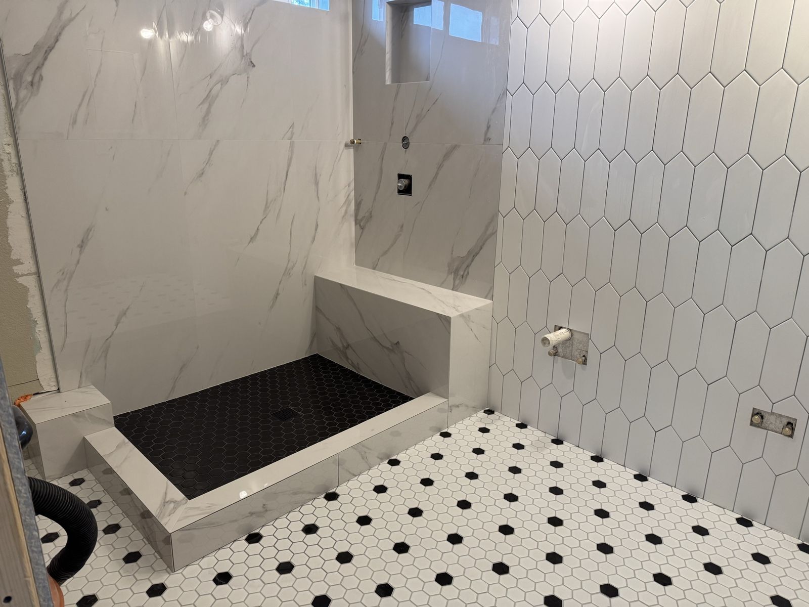 Residential shower with large-format walls and hex mosaic floor during install