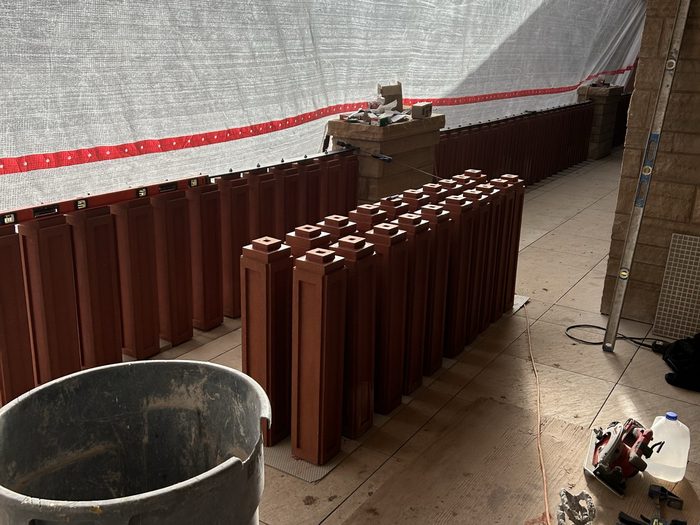 Terracotta balusters staged on the covered balcony alongside the mortar mixer and tools.