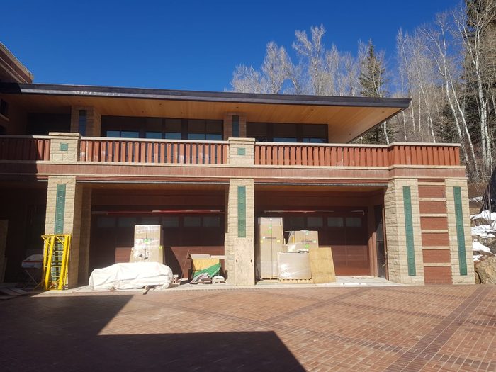 Entry pillars during construction — four green terracotta inlays set into the stone, materials staged on the pavers.