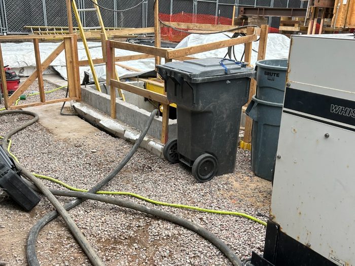 Generator and hose run laid out across the gravel to the building.