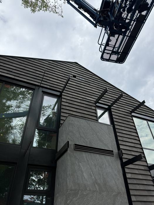 Corner where dark horizontal siding meets steel window frames.