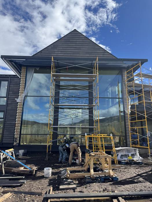 Large glass window set into a dark steel frame, scaffolded.