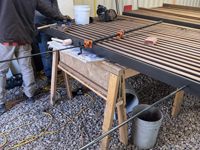 Slats hammered into the frame on sawhorses, pipe clamps holding it square.